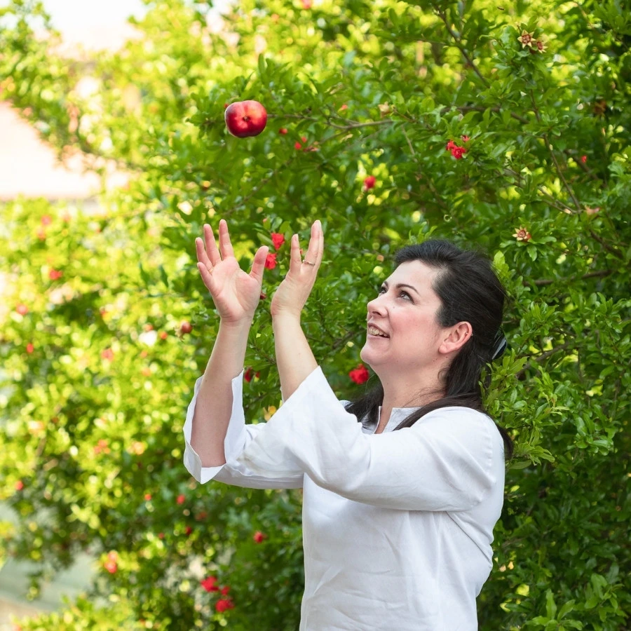 Marzia Vignoni felice in un frutteto che lancia in aria una pesca.